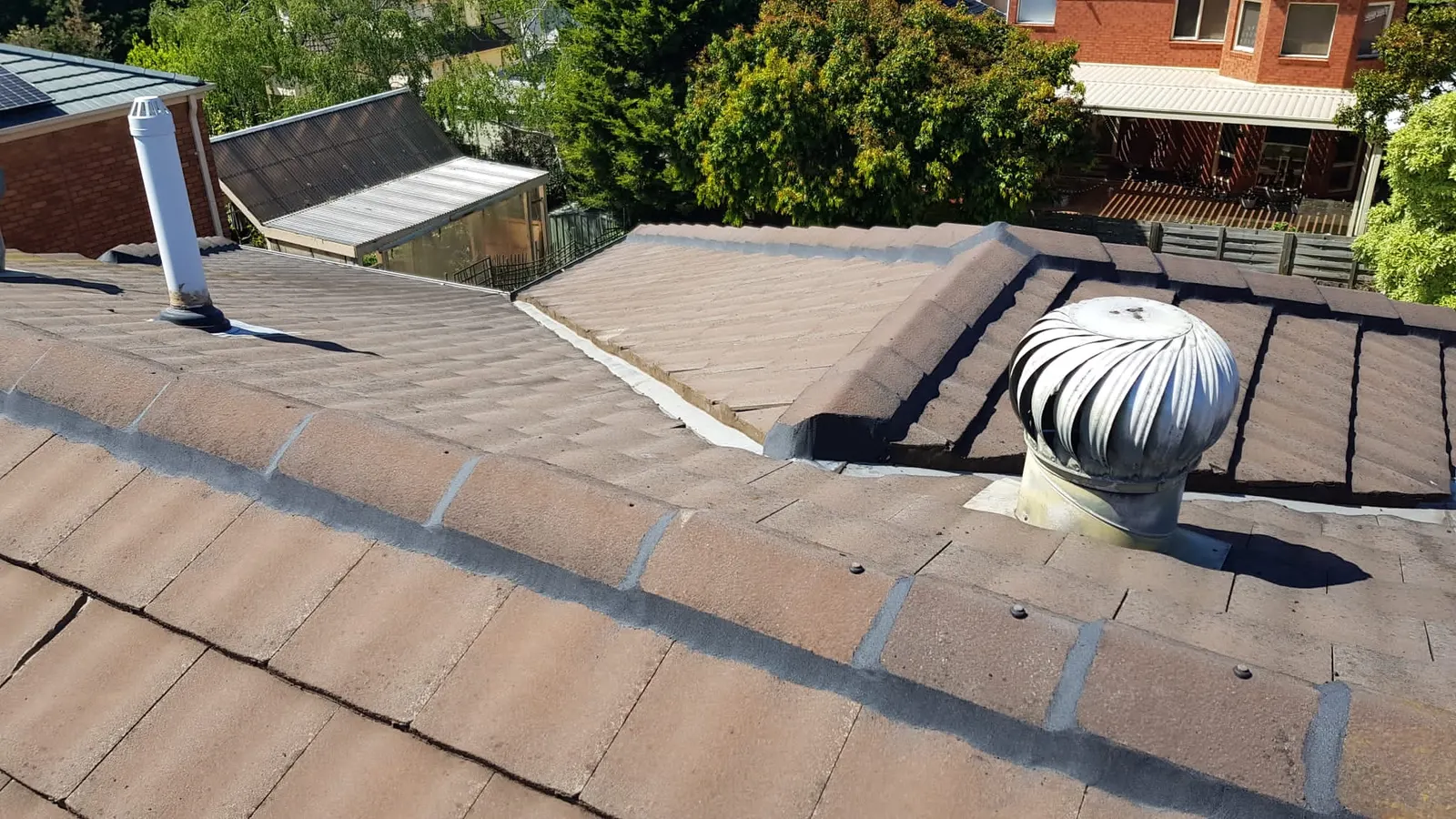 Concrete tiled roof showing renewed ridge pointing around a roof ventilator