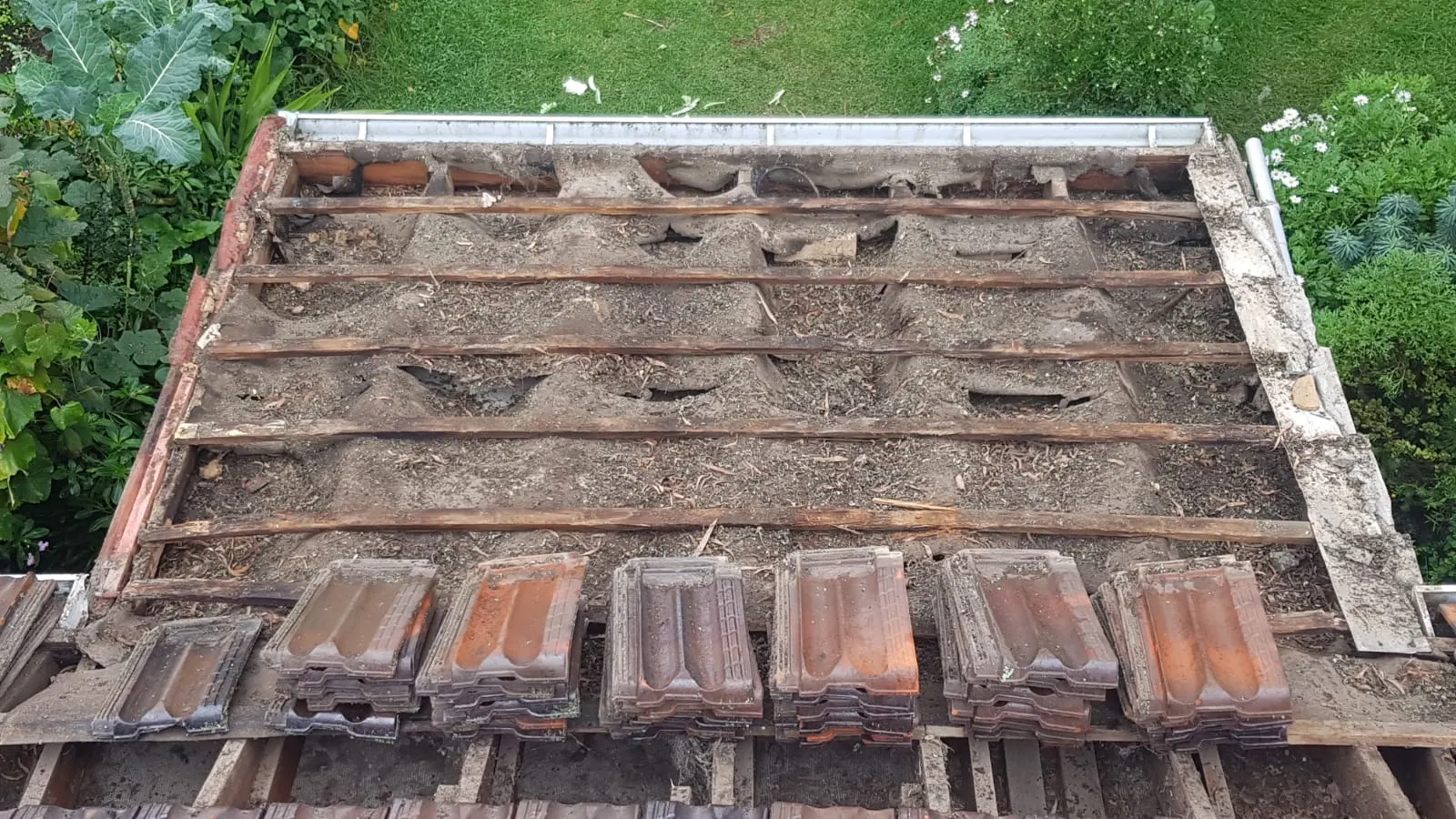 Tiled roof section stripped back to expose battens before repair work